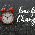 Red alarm clock on asphalt with text "Time for Change," symbolizing dealing with continuous change.