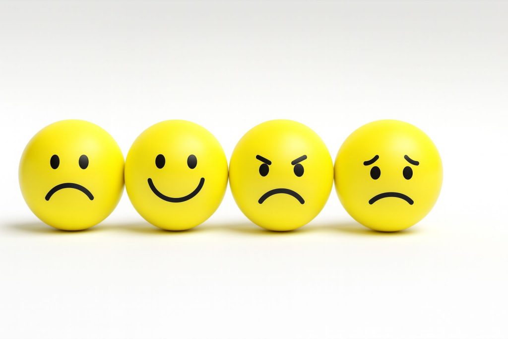 Four yellow emoji balls displaying a kaleidoscope of emotions: happy, sad, angry, and confused.