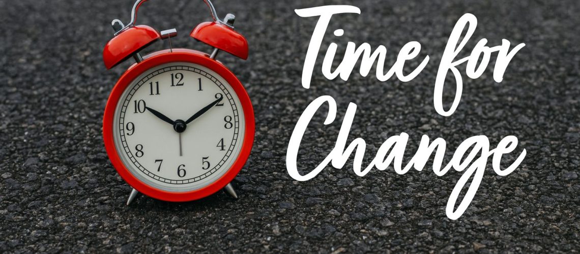 Red alarm clock on asphalt with text "Time for Change," symbolizing dealing with continuous change.